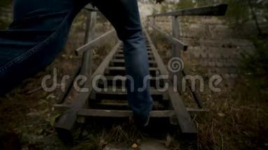 男人上楼梯。 录像。 两侧草地上的一座小山上的老<strong>木台阶</strong>。 上草的<strong>木</strong>楼梯